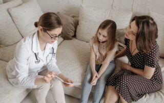 Doctor explaining concierge primary care options to a mother and daughter during a family office visit.