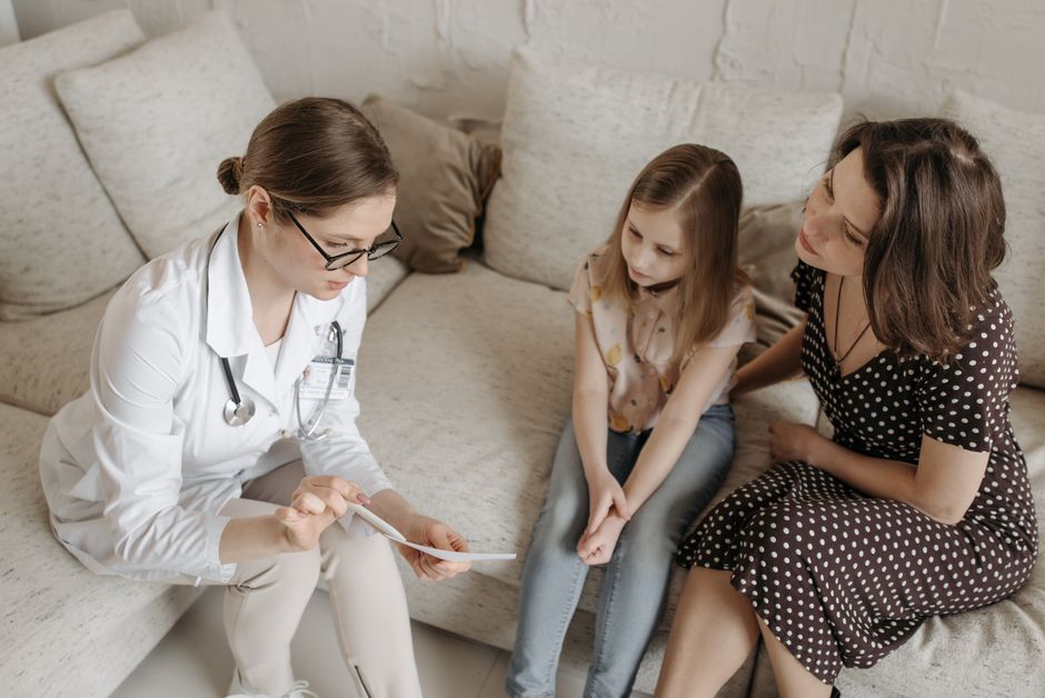 Doctor explaining concierge primary care options to a mother and daughter during a family office visit.